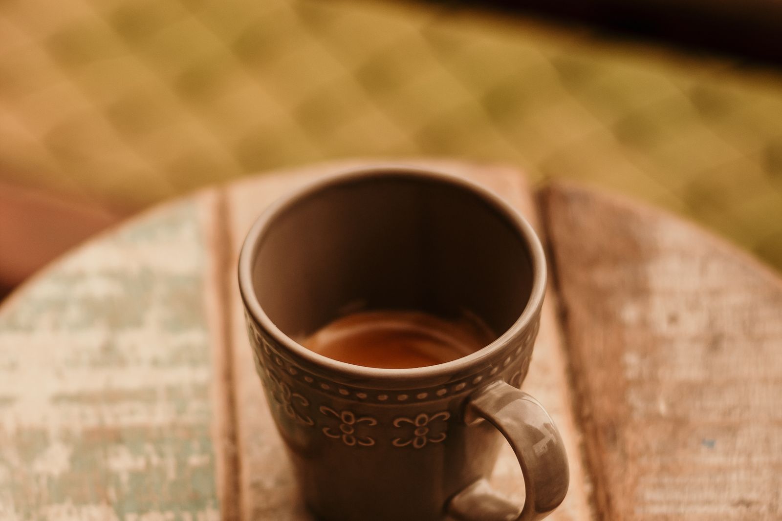 A cup of coffee on a wooden desk.