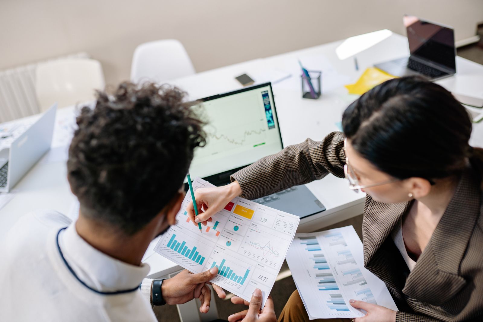 Two colleagues reviewing financial charts together at a desk.