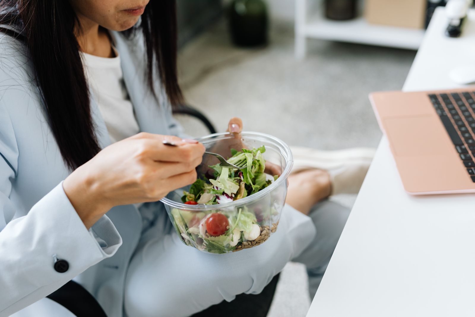 An office worker eating a healthy salad at their desk.