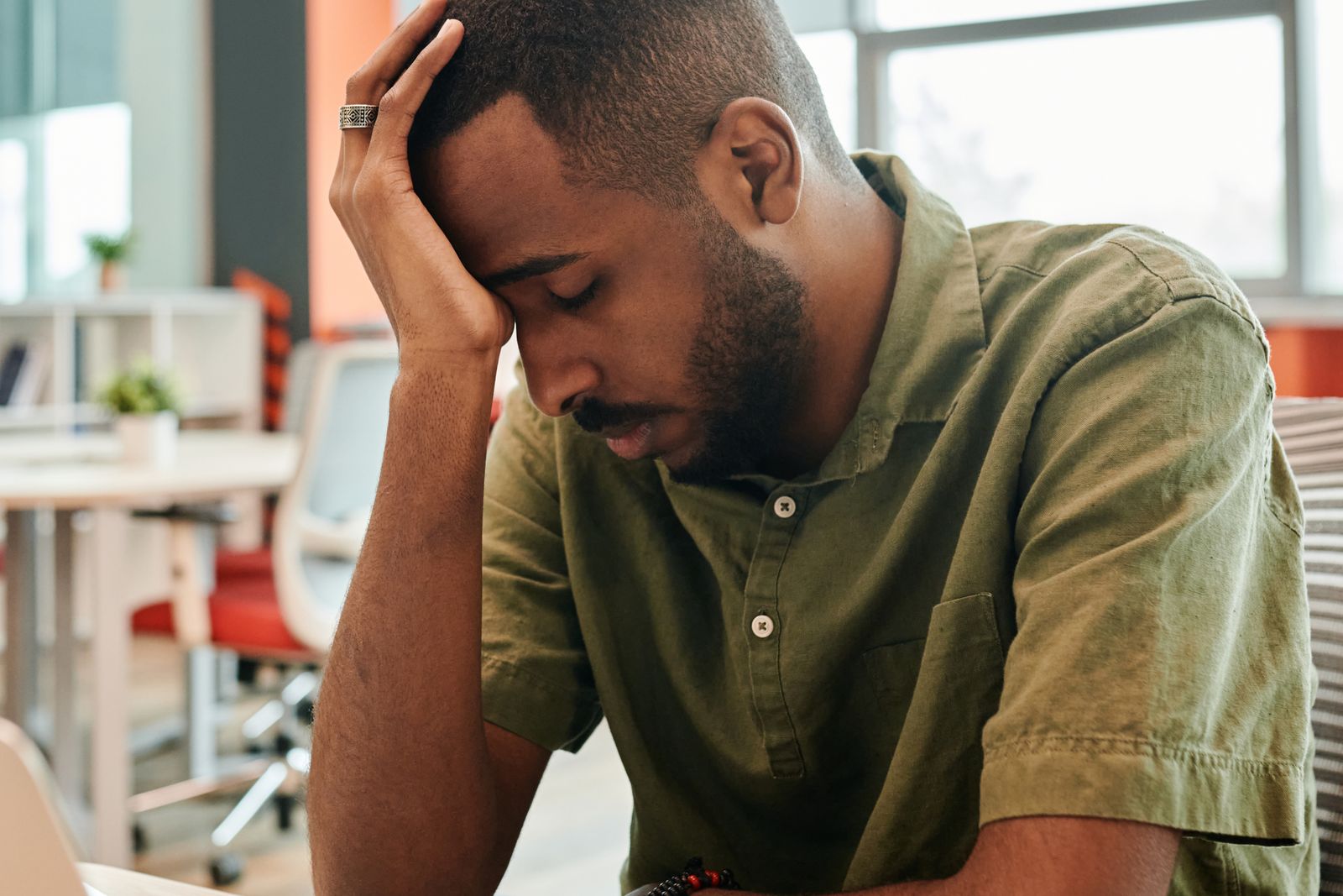 A tired office worker slumped at a desk in front of a laptop.